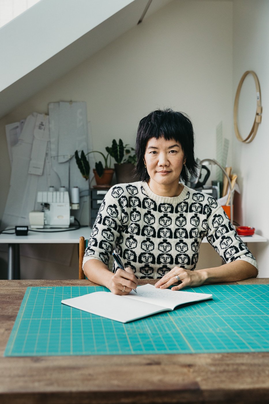 Artist Hope Meng sits at drafting table with open notebook, shot in studio during brand session in San Francisco.