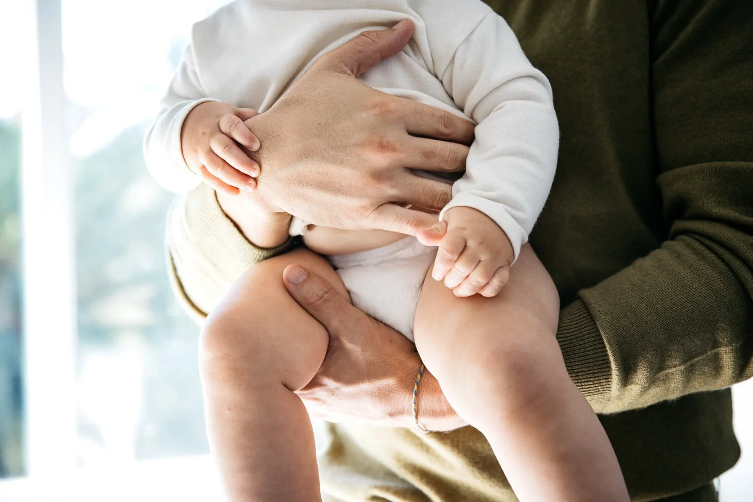 Dad and baby stand near window, as window light softly wraps around them. Shot at home in Larkspur.