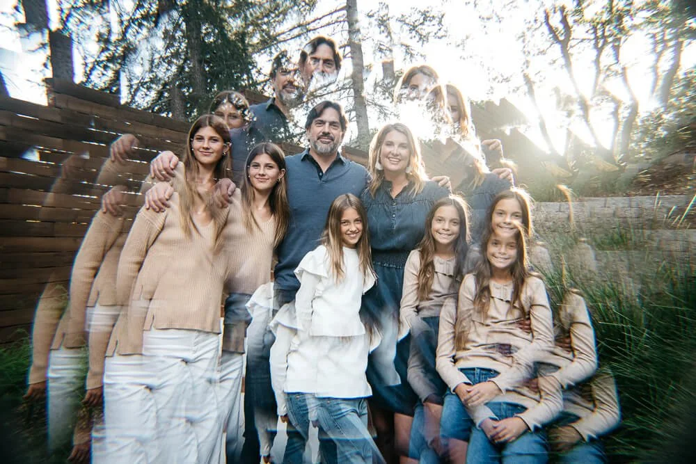 Kaleidoscope image of family of five with three teen daughters, as they stand in backyard with setting sun behind them.
