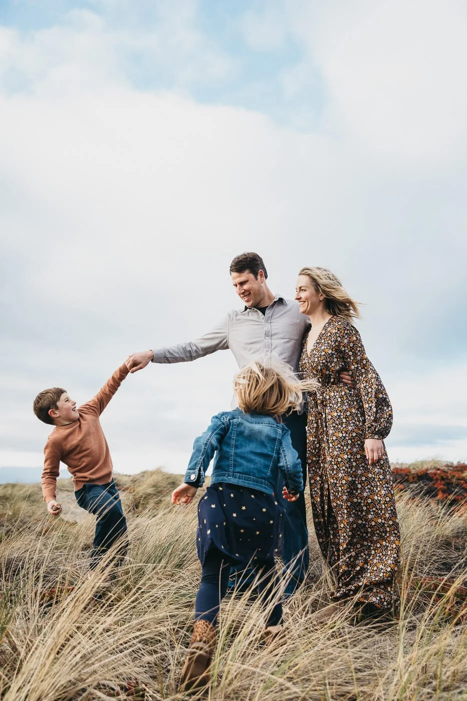 Family of four dances in the sand dunes at Ocean Beach in San Francisco.