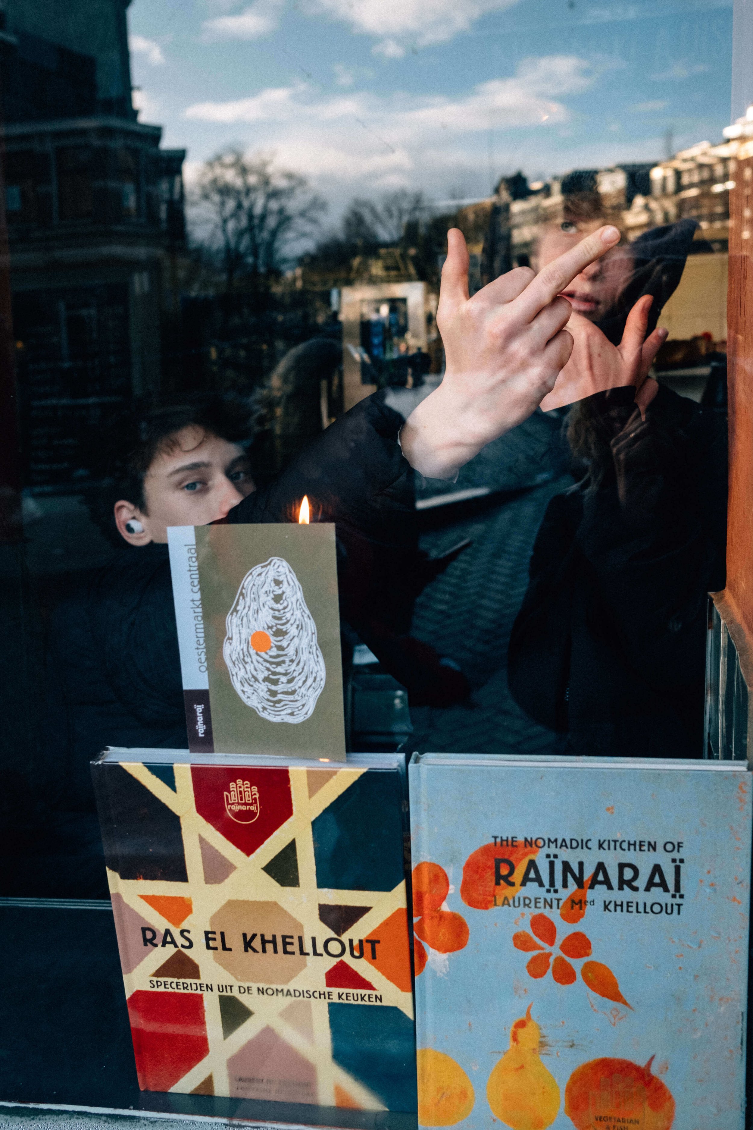 Teen boys flip off camera from the other side of a window.