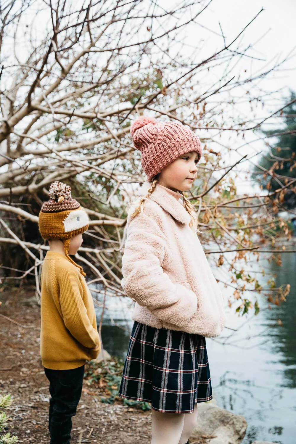 Siblings stand at pond's edge at Palace of Fine Arts wearing muted fall colors.
