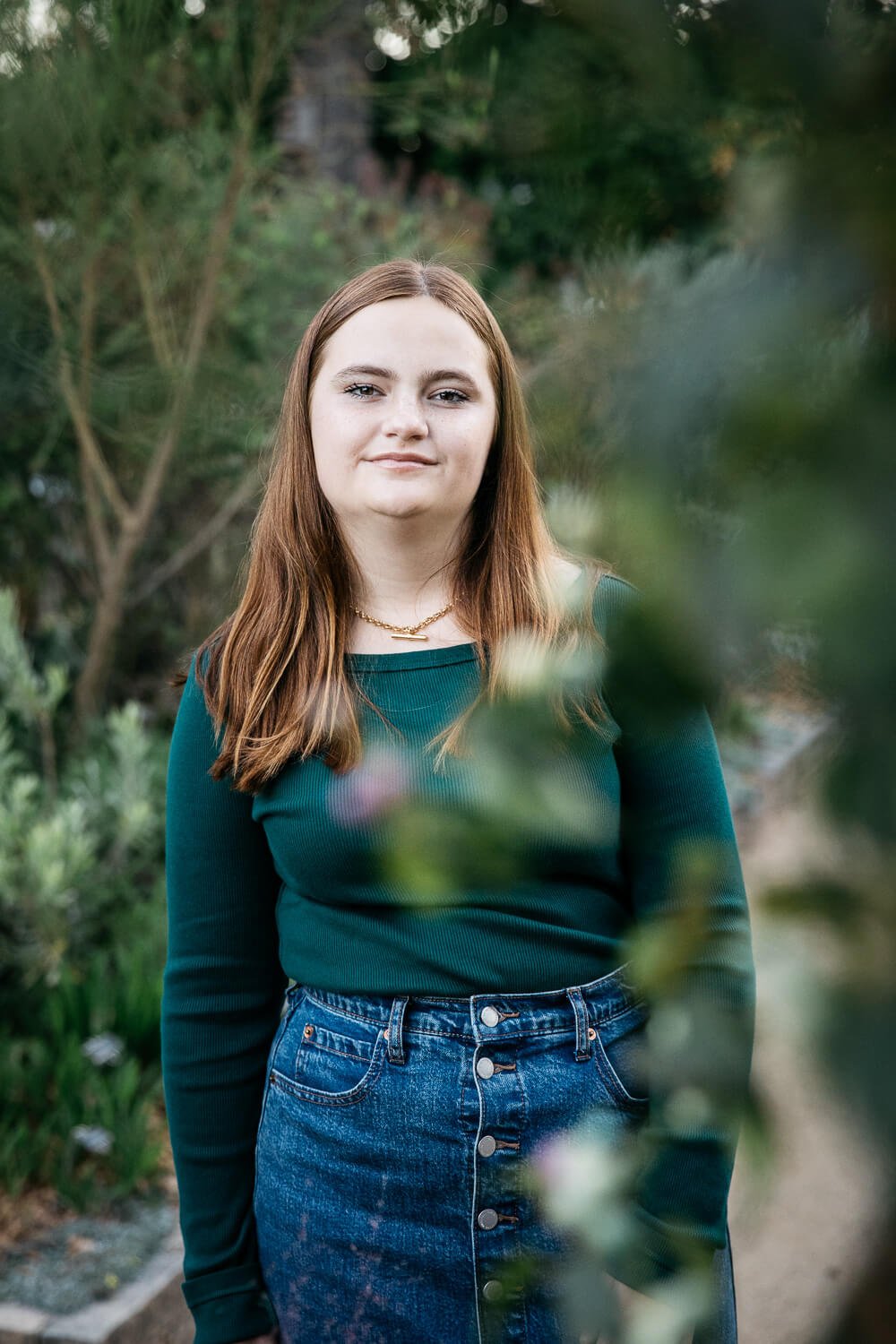 Teen in dark green shirt stands among greenery at Gamble Gardens in Palo Alto.