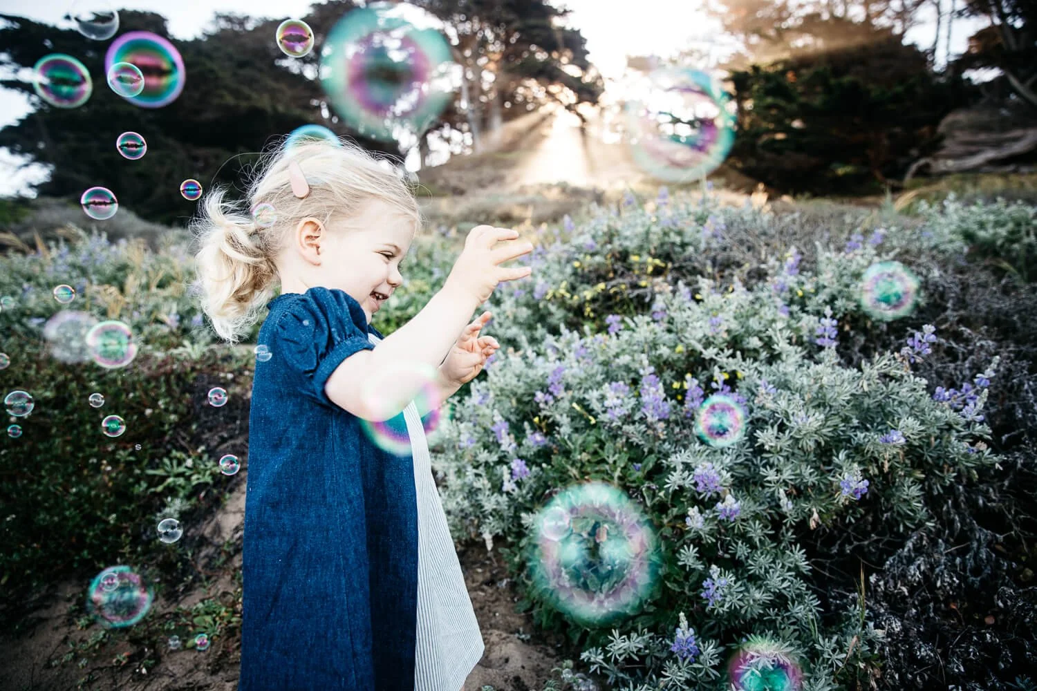 Toddler model for Ellis Littles runs through lupins and bubbles, shot at Baker Beach in San Francisco.