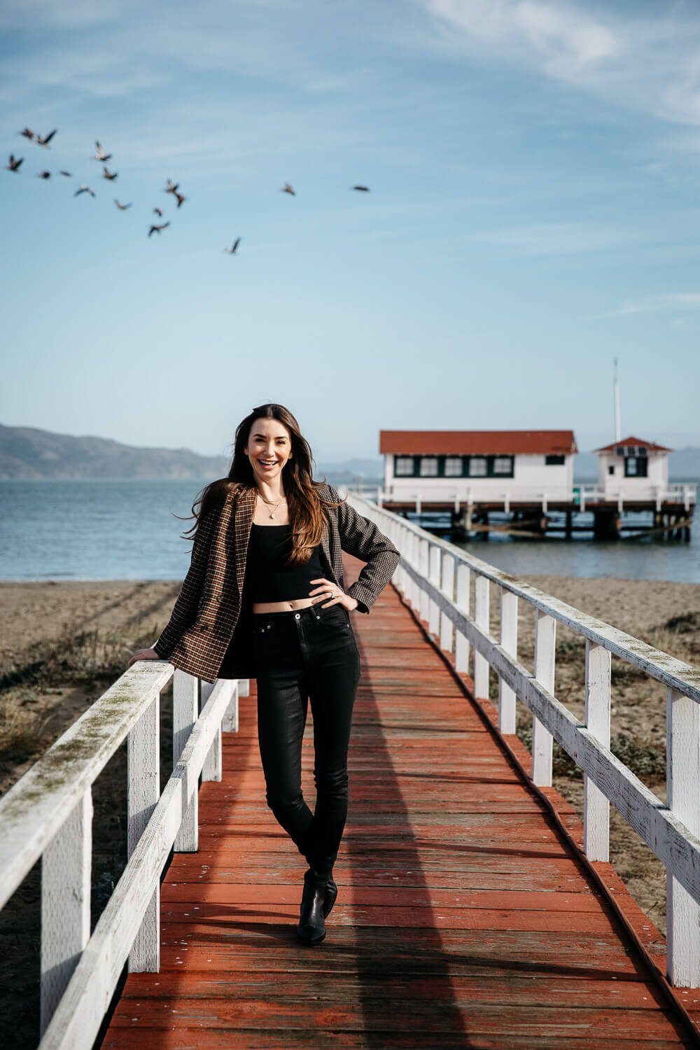 Woman in black tank and leggings stands on a wooden pier at Crissy Field Beach in San Francisco.