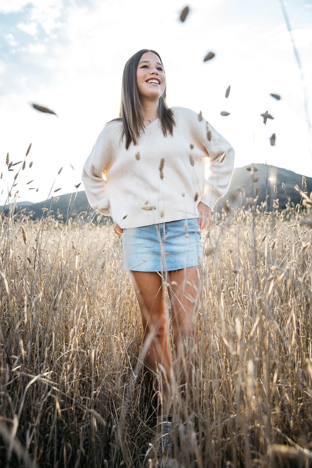 Teen girl stands in tall, golden grass and laughs, shot in the Marin Headlands.