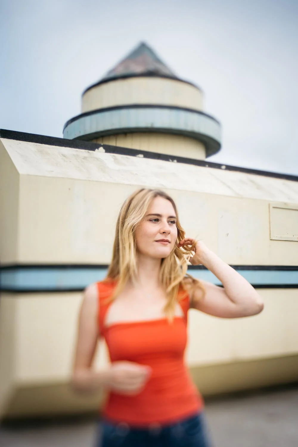 Teen girl with long blond hair, wearing a salmon-colored tank and jeans stands in front of the Giant Camera at The Cliffhouse in San Francisco.
