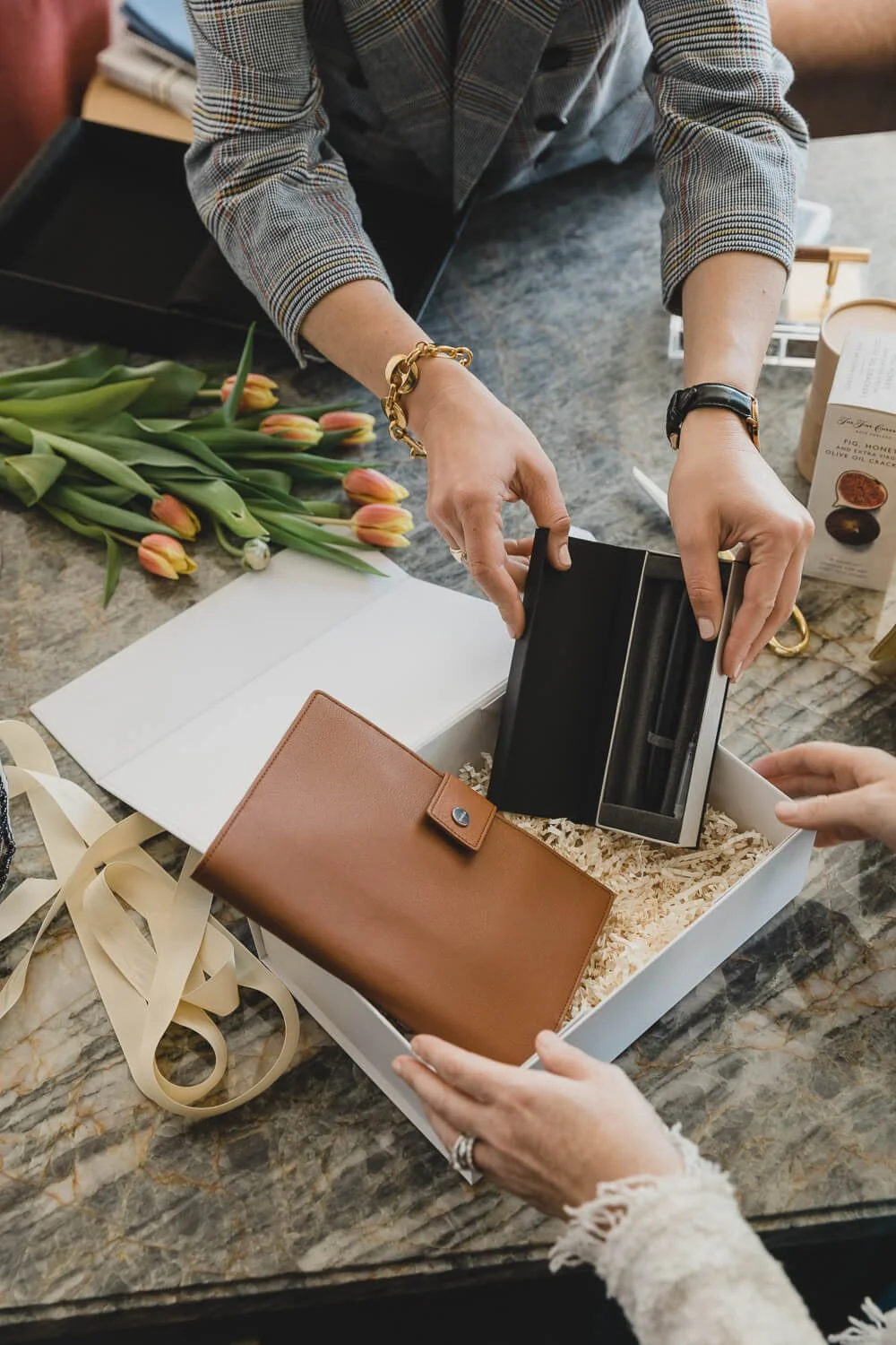 Hands placing leather wallets into gift box, shot for Poppy Gifting in San Francisco.