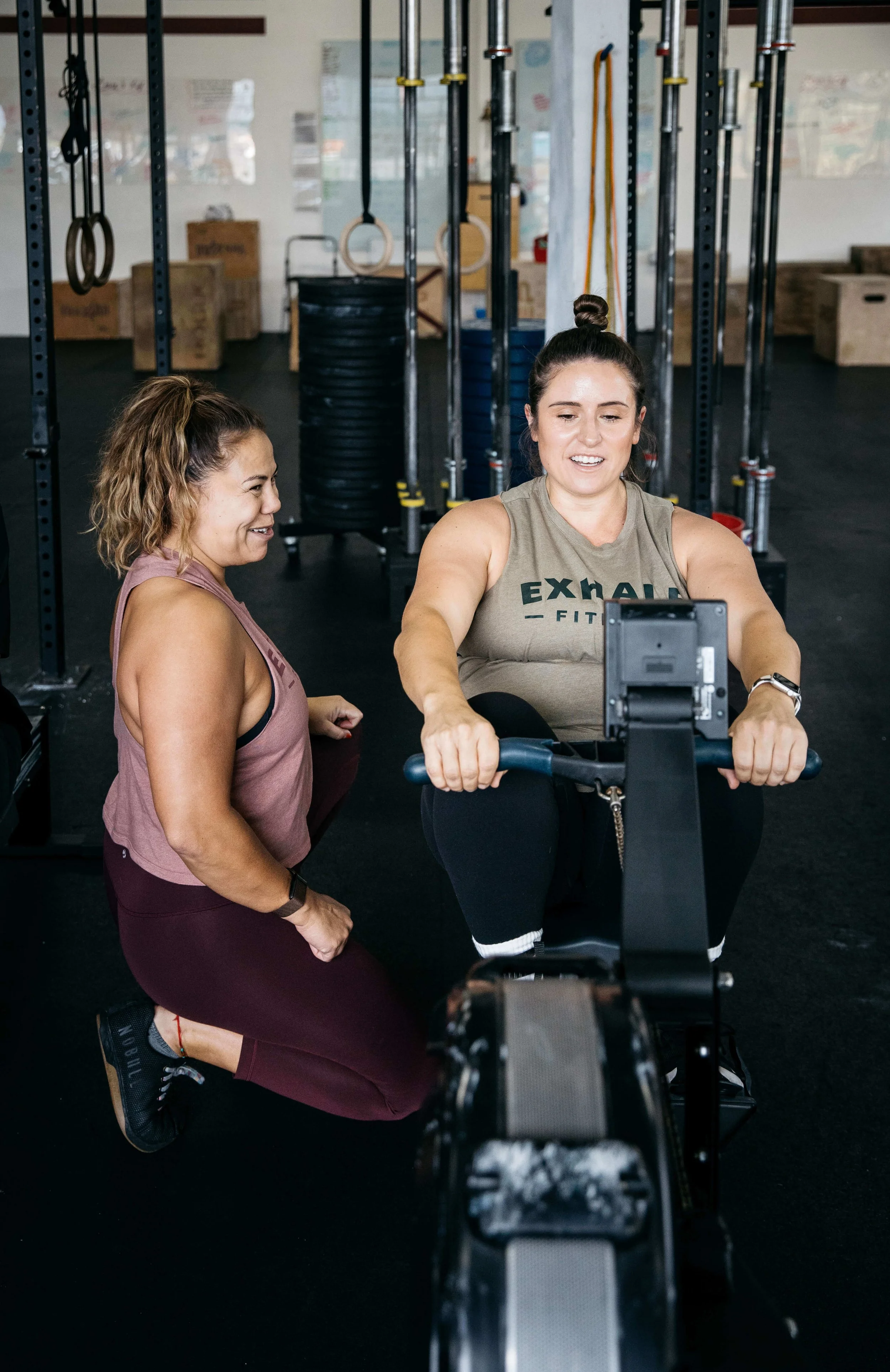 Crossfit coach helps woman on rowing machine, shot for Exhale Gym in Richmond, CA.