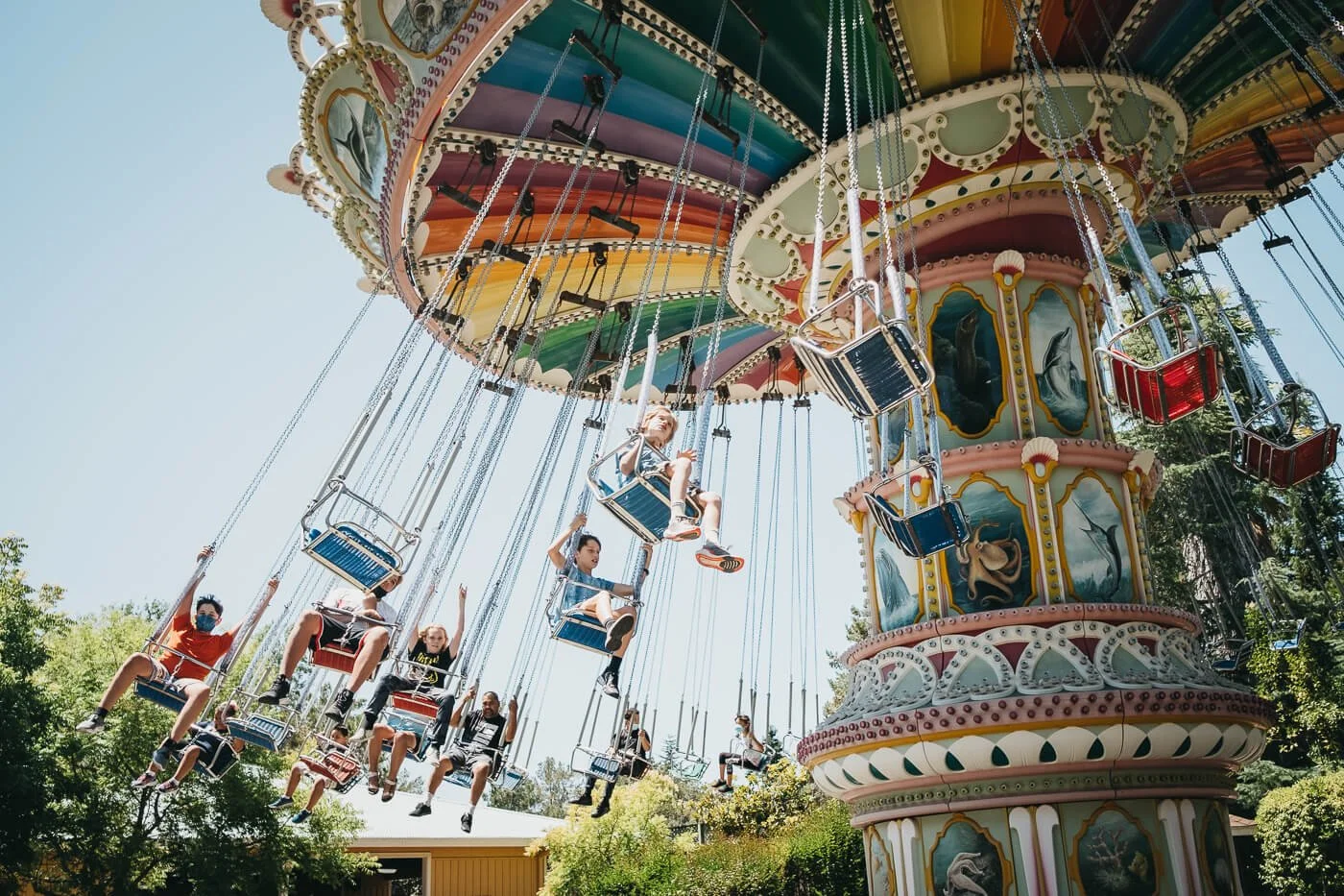 People riding colorful swing carousel, shot from down low.