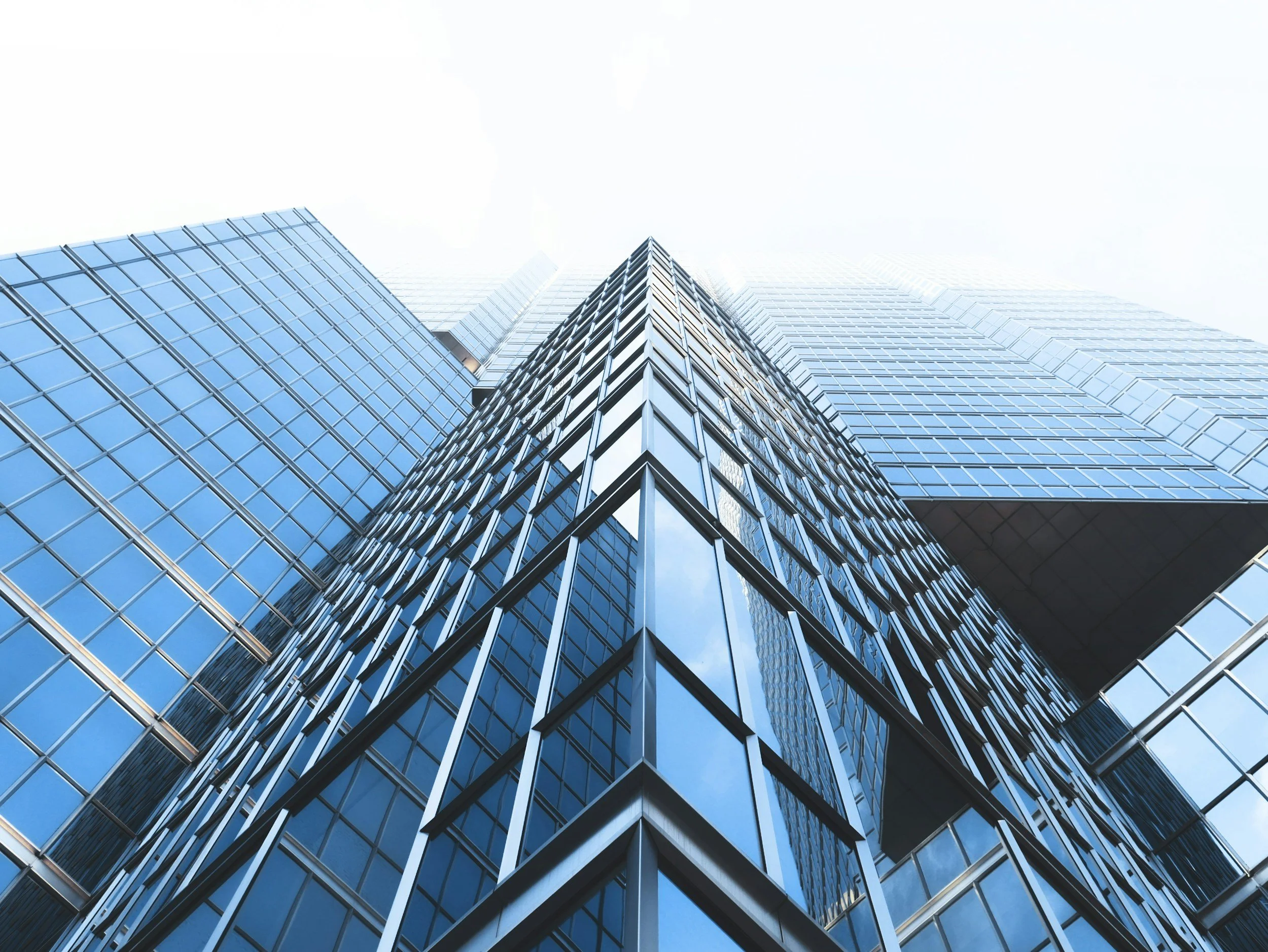 Low-angle black and white photograph of modern glass skyscrapers from the street level.