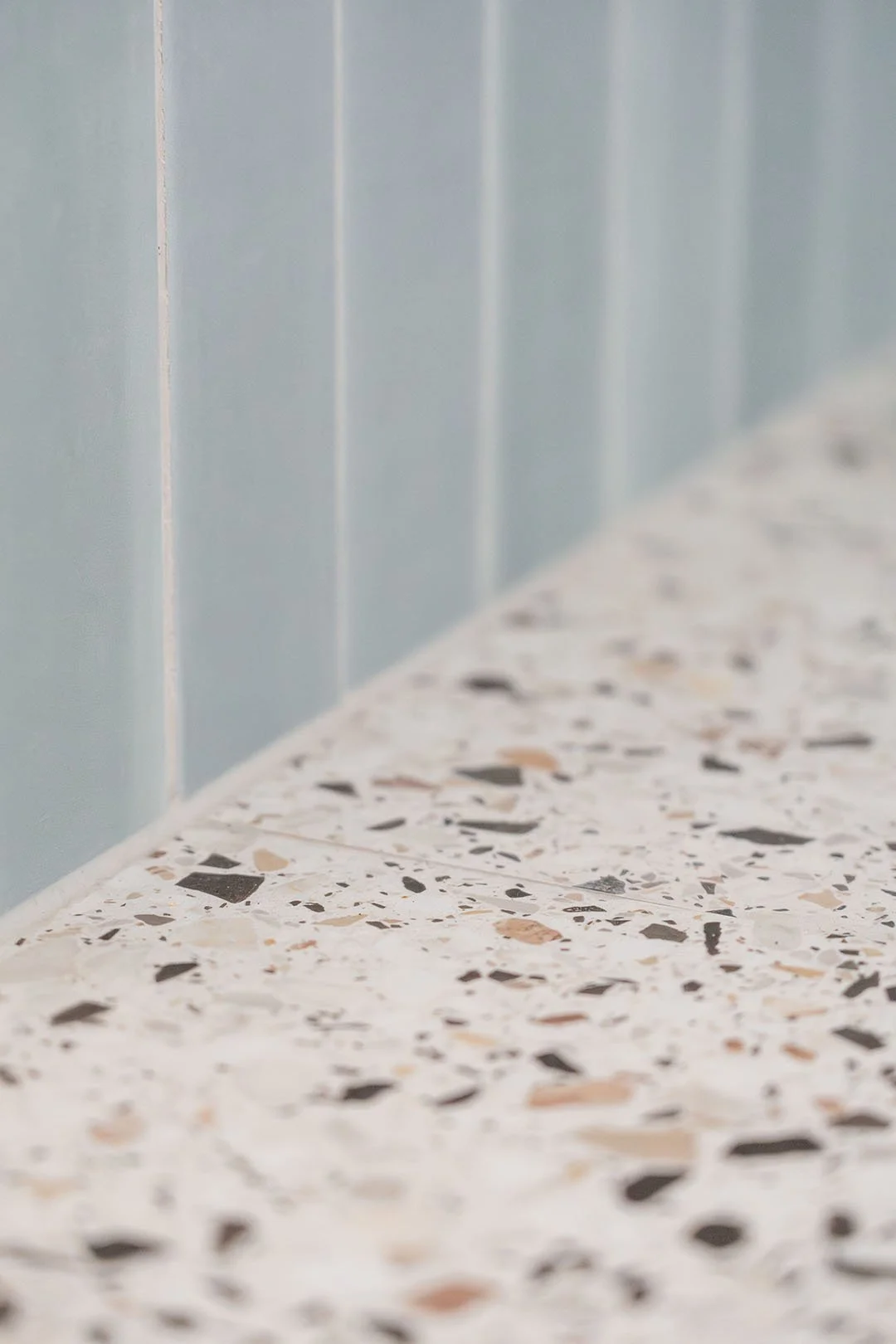 Flisegulv med terrazzo-mønster foran blå vægge.