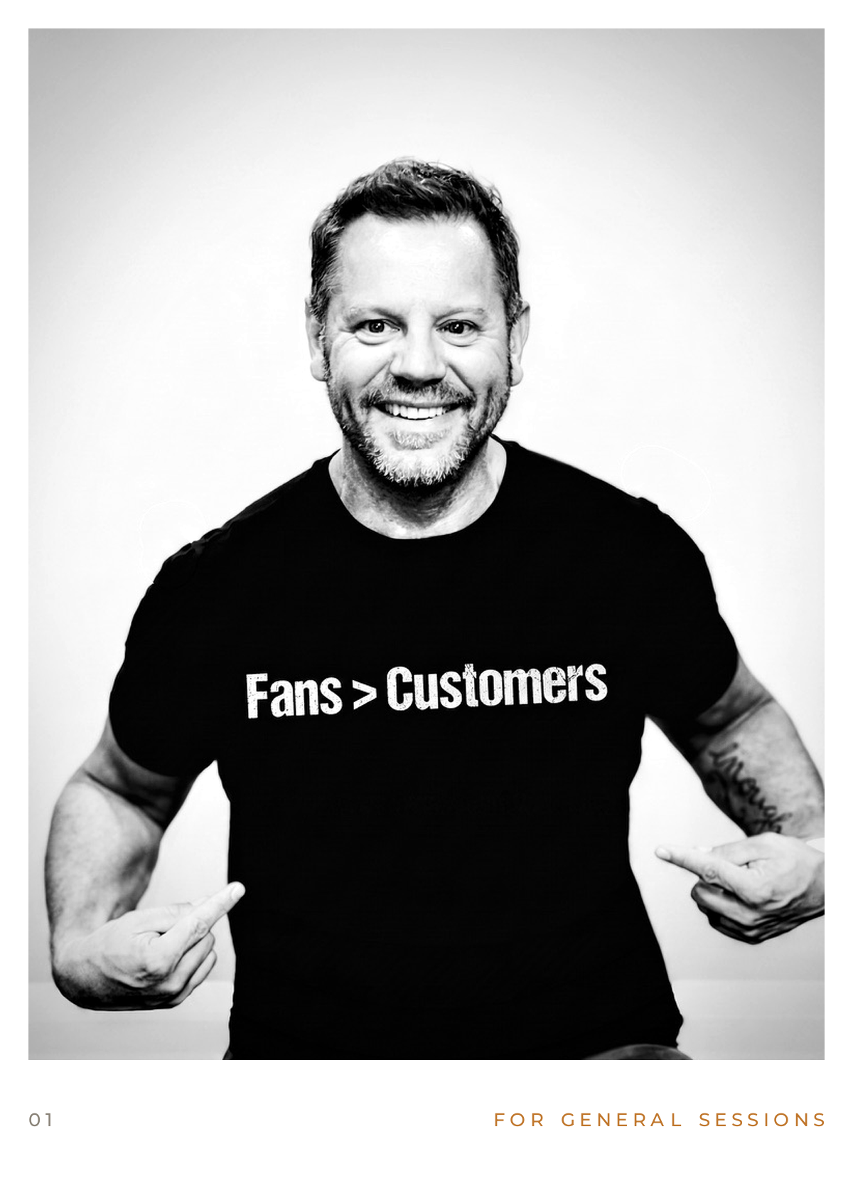 Black and white photo of a smiling man with facial hair, wearing a black t-shirt that says "Fans > Customers," pointing to the word "Fans" with both hands.