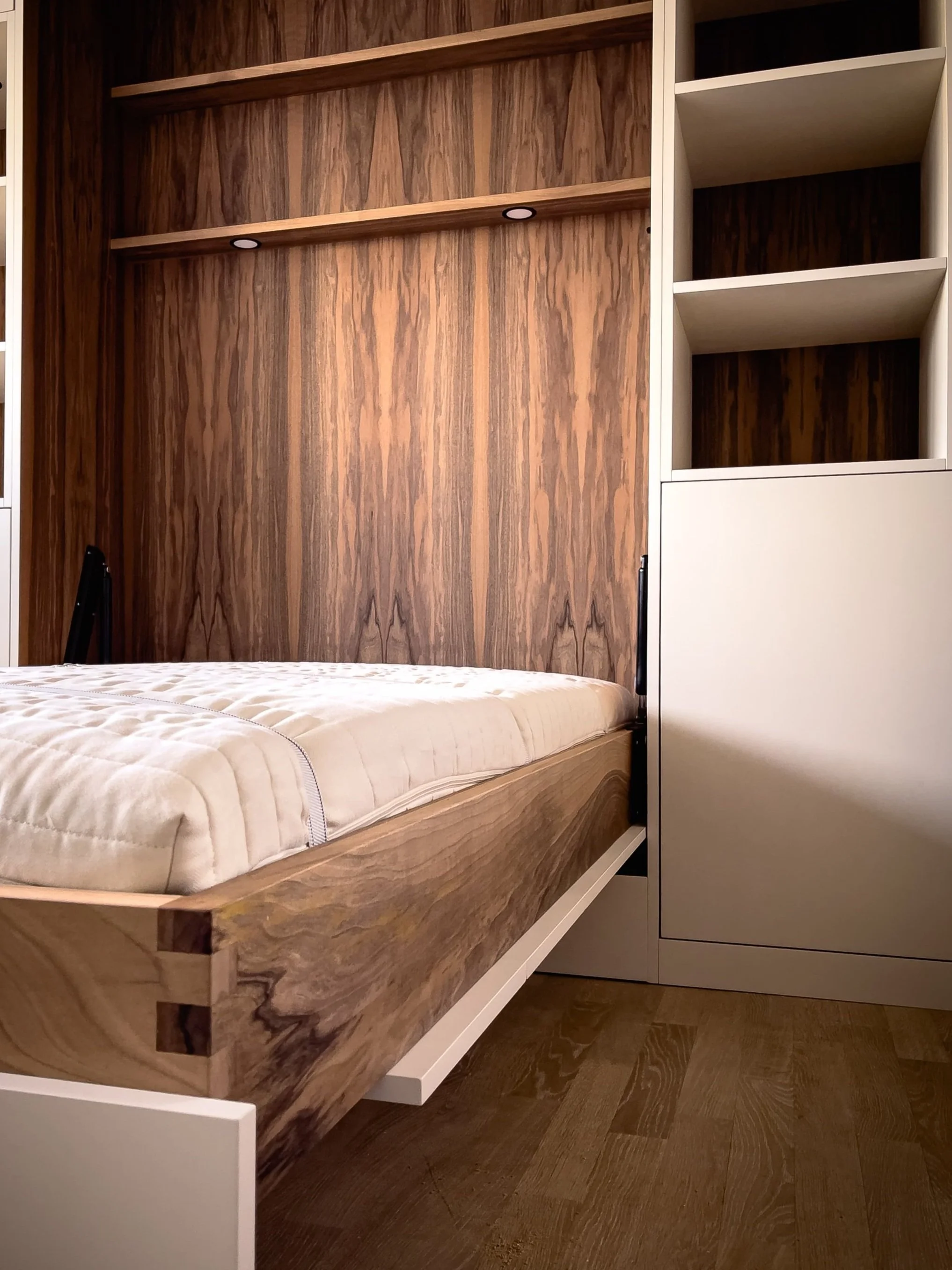 Ein modernes Schlafzimmer mit Holzwand, einem weißen Bettgestell und offenem Stauraum.