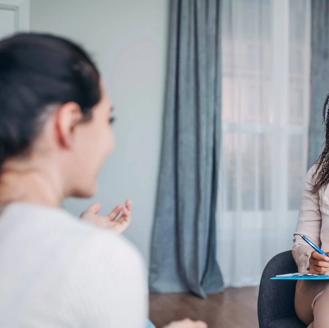 Side view of a woman in conversation during a coaching session, suggesting support and guided exploration.