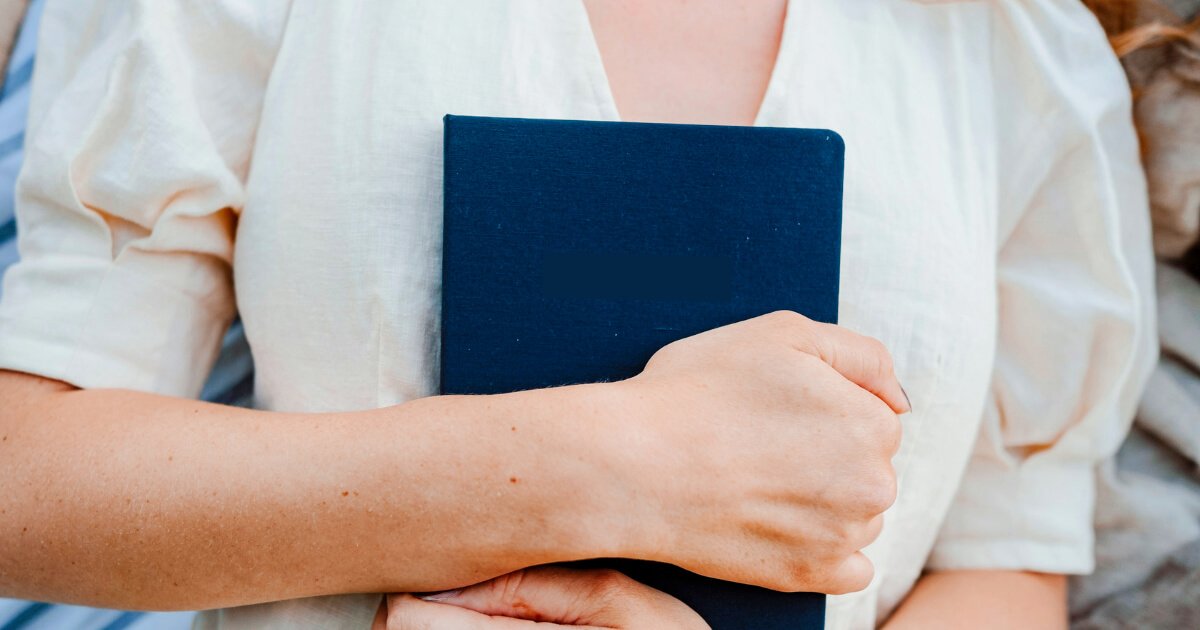Woman holding a journal to her chest, symbolising reconnecting with her inner voice.