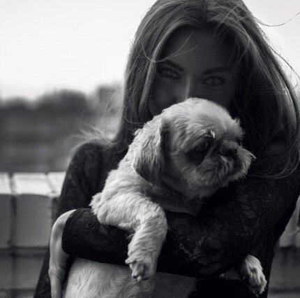 Dostinja holding a small dog on a balcony, black and white photo.