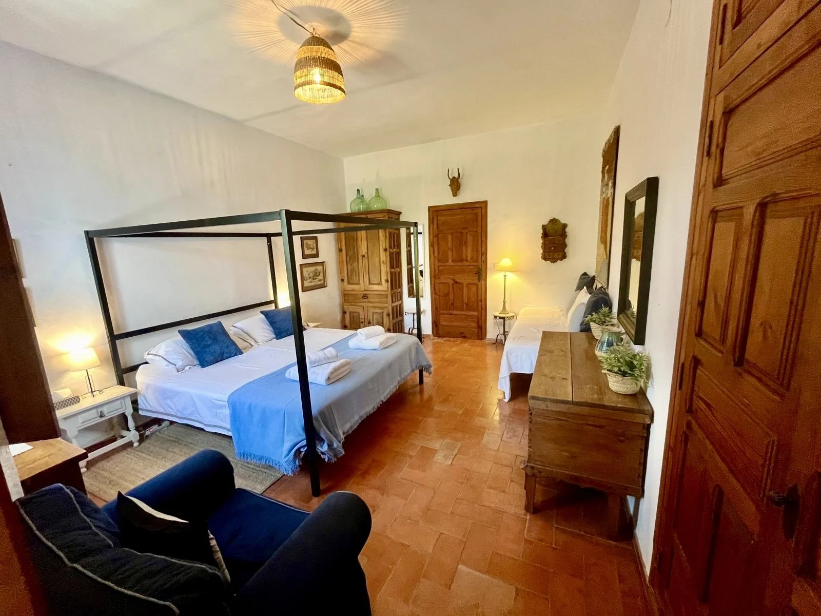 Master bedroom downstairs with air conditioning (2025), four poster super king size bed, separate sofa and ensuite bathroom.