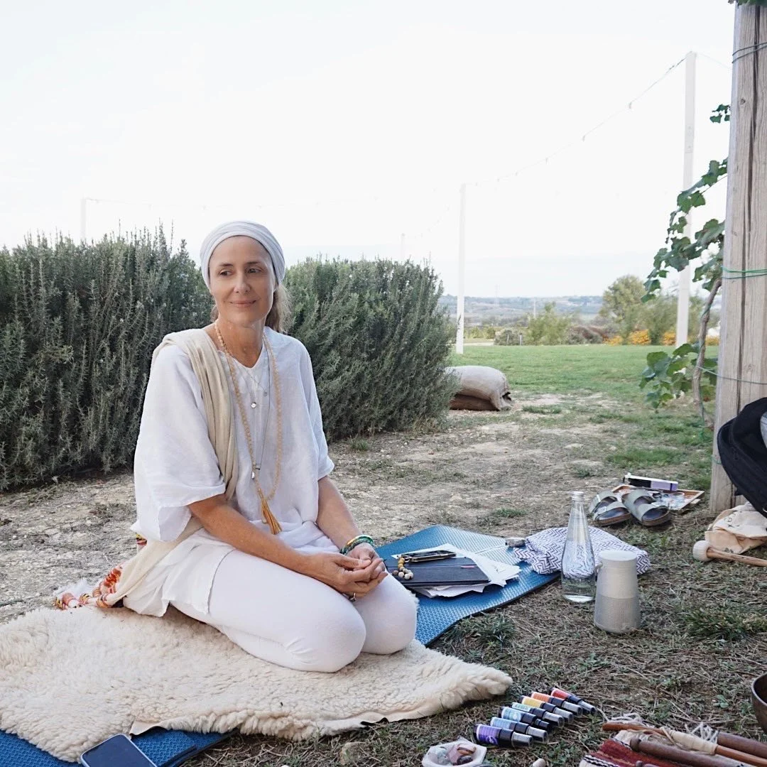 Woman sitting outdoors on a mat with art supplies around her