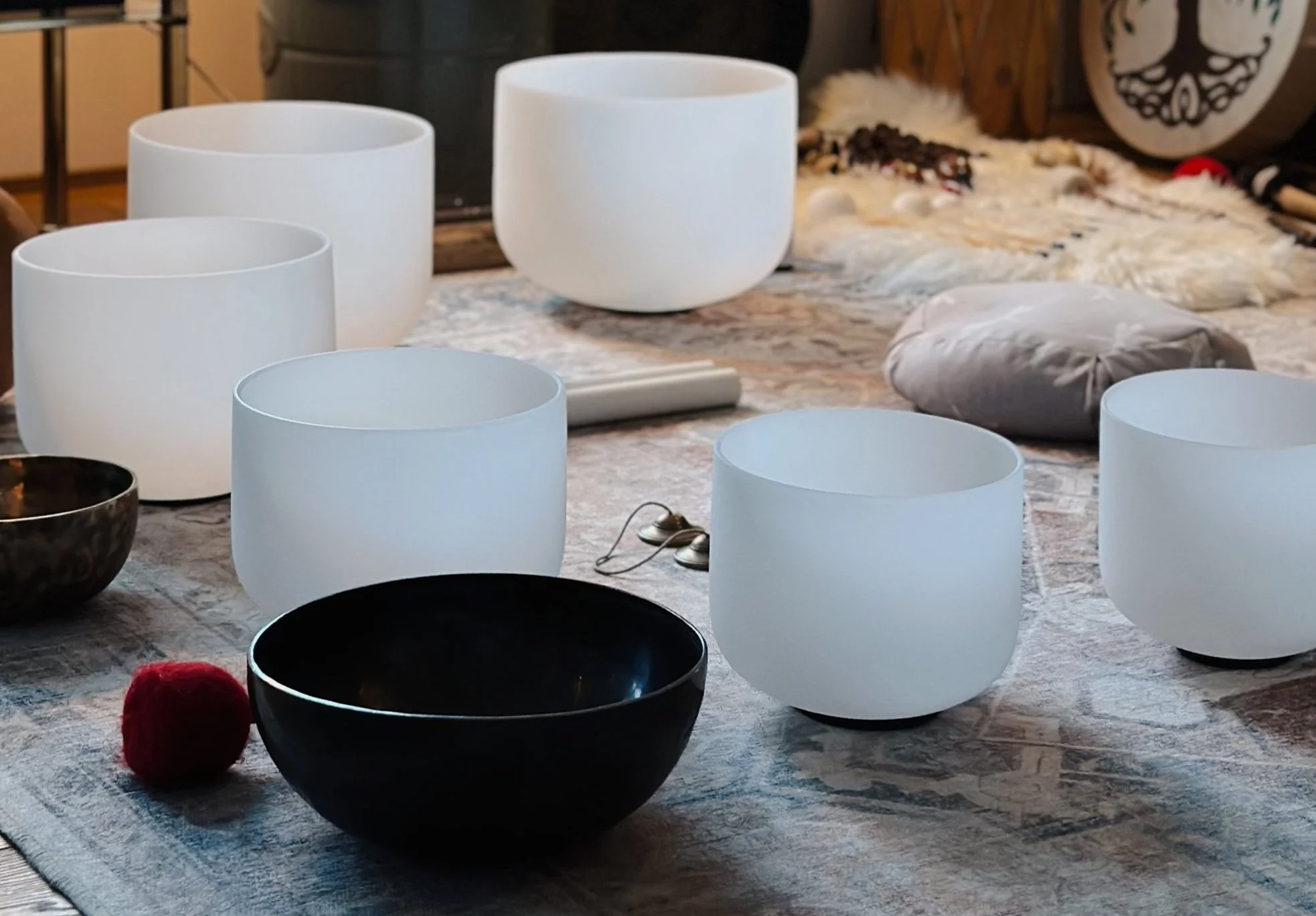 Crystal singing bowls and a meditation space with cushions and mallet.