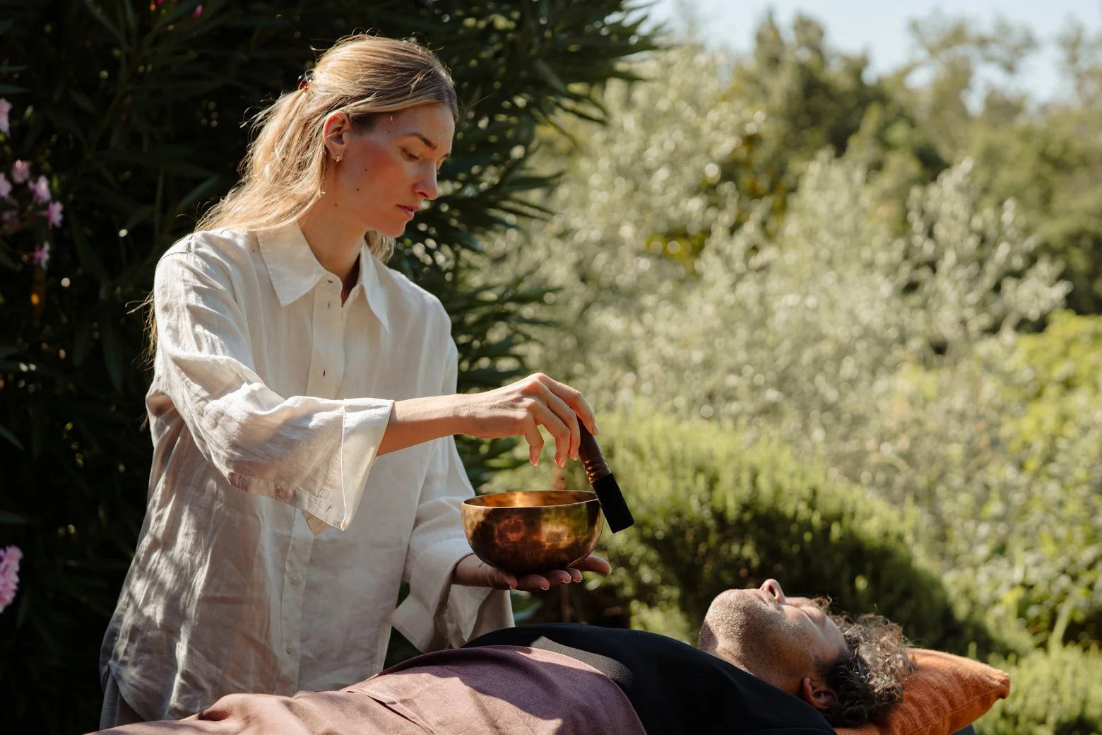 Person holding a singing bowl with a mallet by the ocean