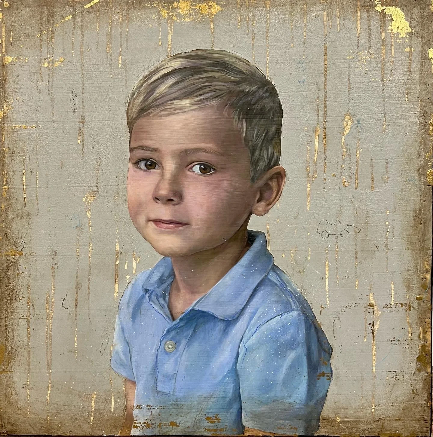 A young boy with short light brown hair and brown eyes, wearing a light blue collared shirt, looking at the camera with a neutral expression, on a textured beige background with gold accents.