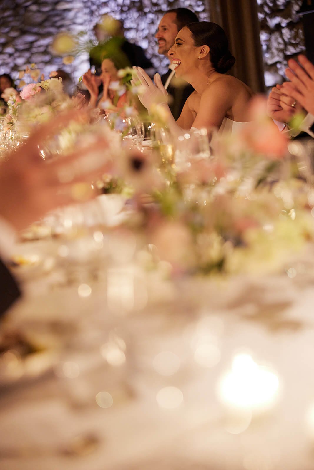 Newlyweds applauded by guests during a blurred-focus wedding reception, highlighting an intimate, joyful celebration