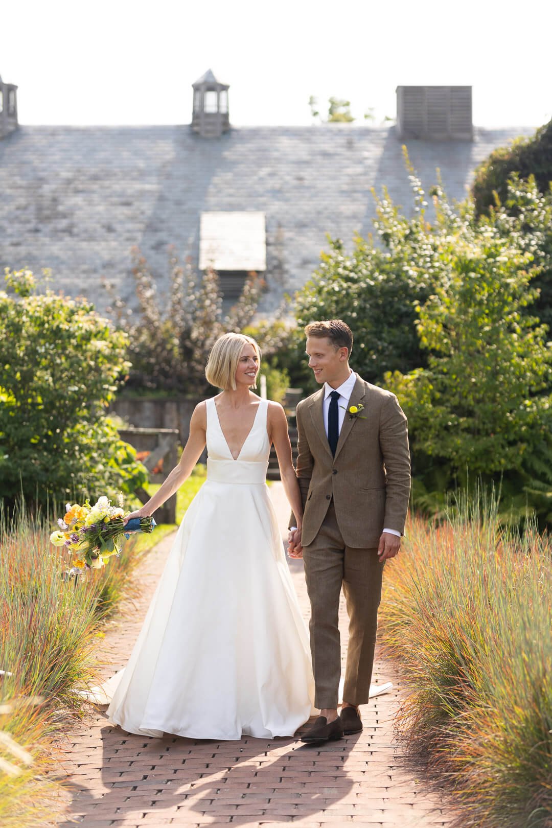 Couple walks hand-in-hand through a serene garden, reflecting a peaceful and natural wedding setting.