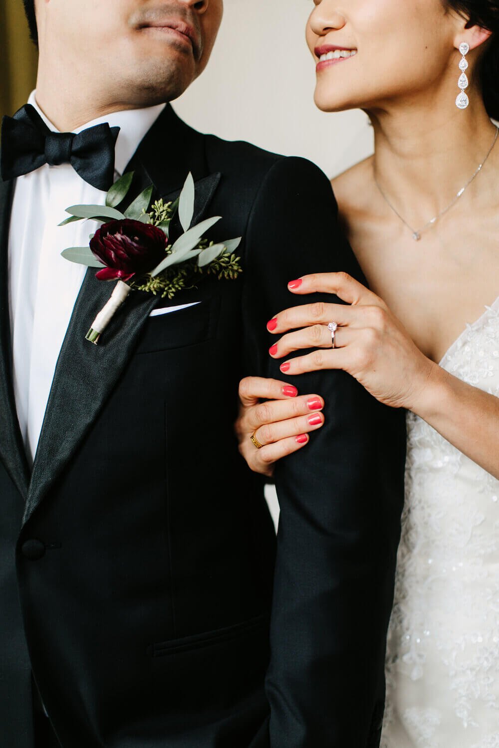 Close-up of a bride and groom, focusing on their loving embrace and the details of the bride's dress and groom's boutonniere.