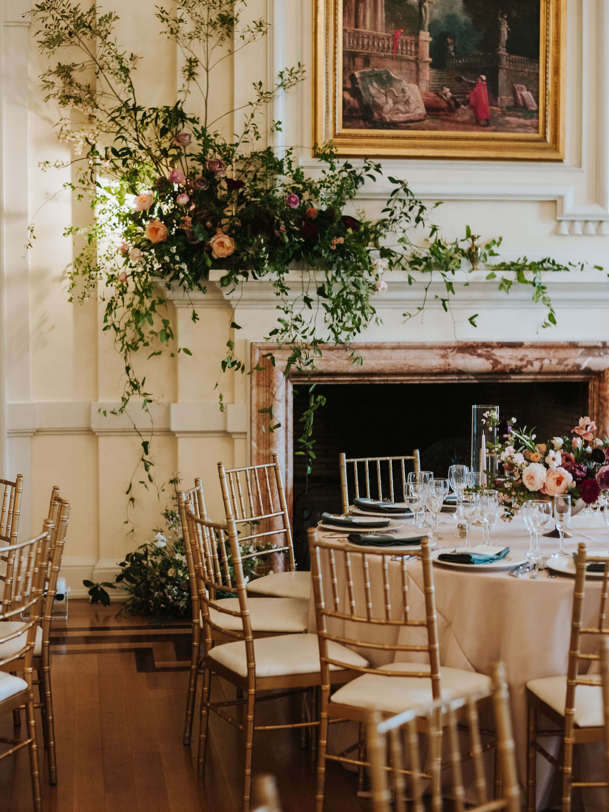 Charming wedding ceremony setup with floral-adorned chairs and an ornate fireplace, inviting an intimate and stylish ambiance.