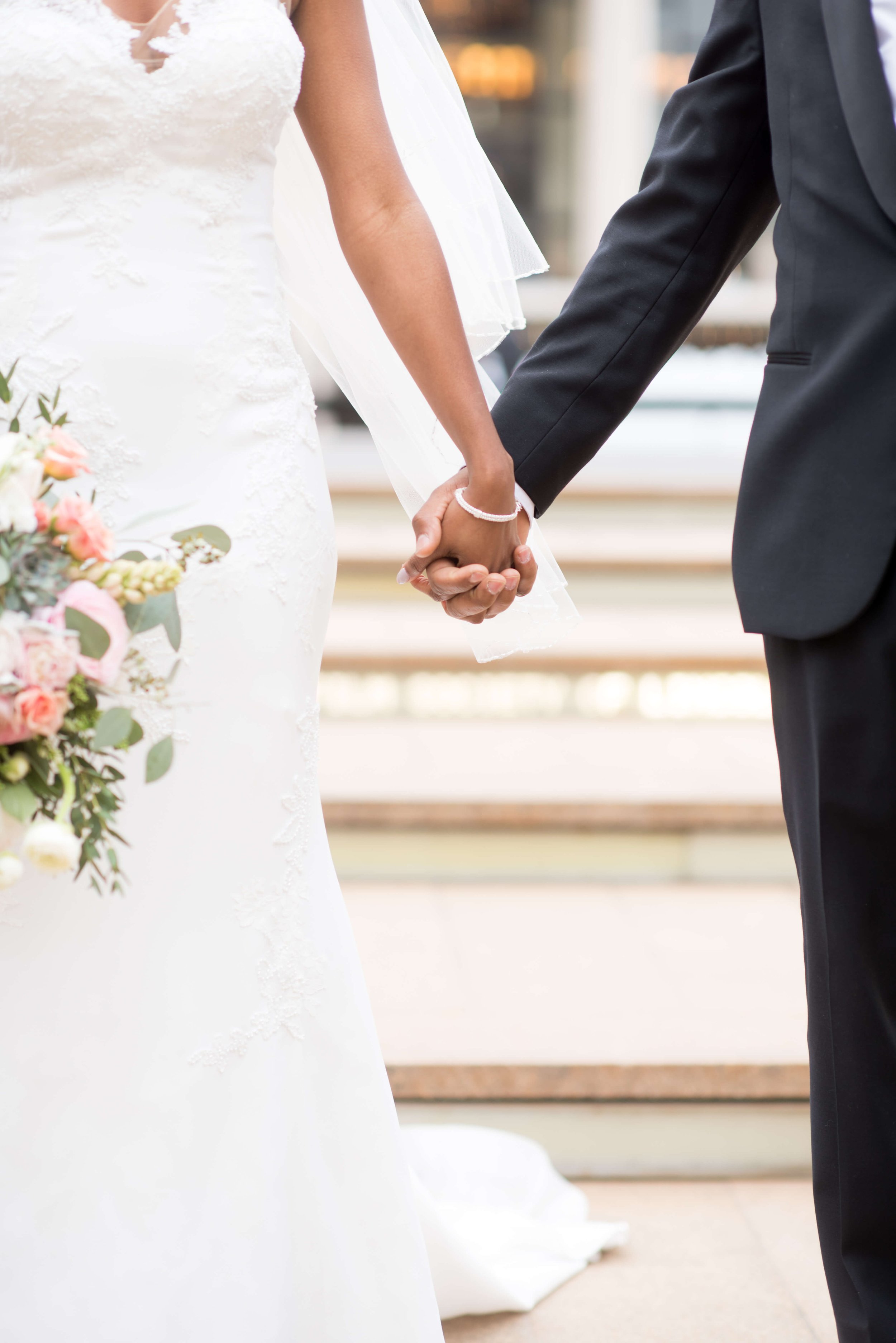Bride and groom holding hands, showcasing their wedding attire and unity in a candid, heartfelt moment.