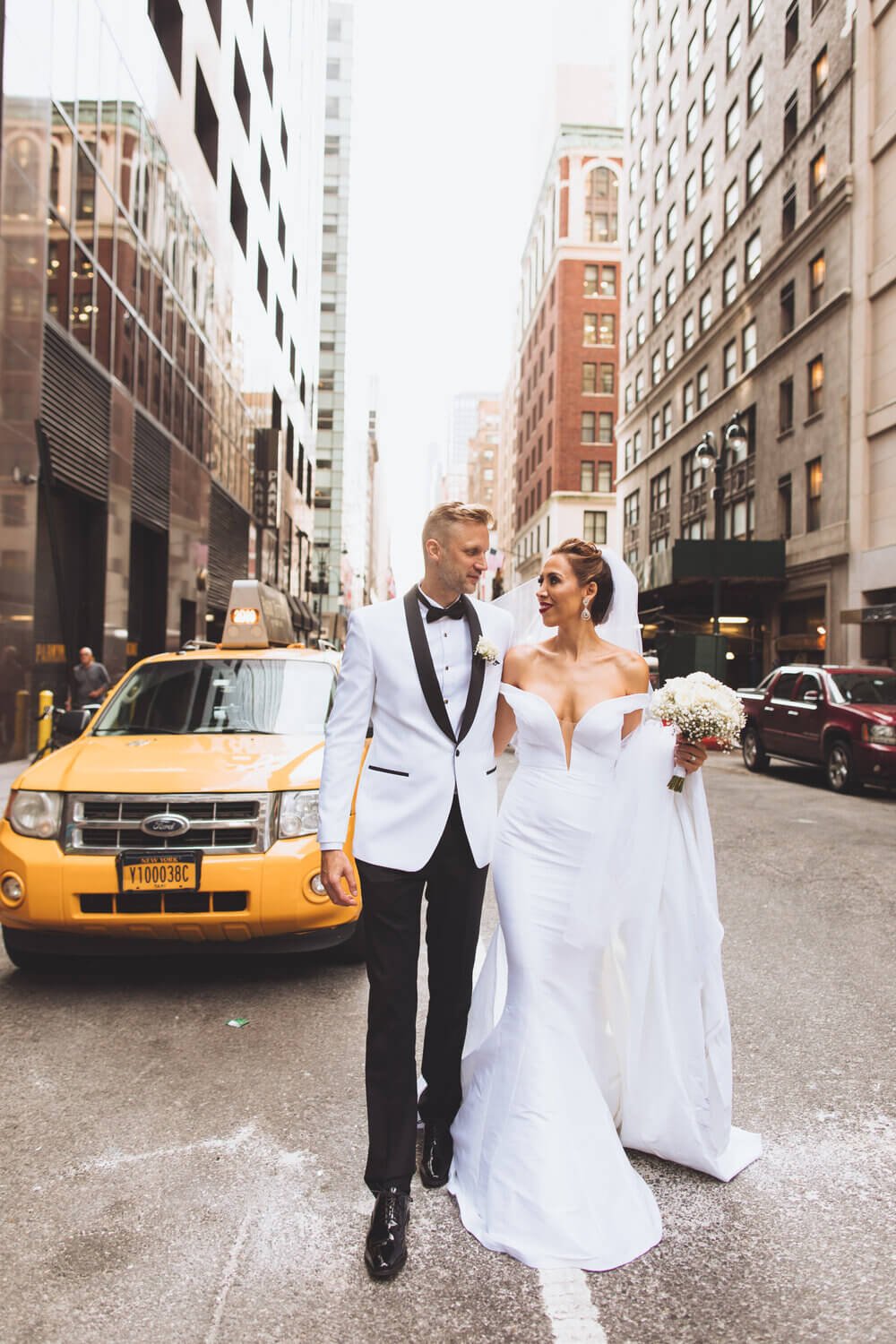 Chic bride and groom walking through busy NYC streets, encapsulating the urban elegance of a city wedding