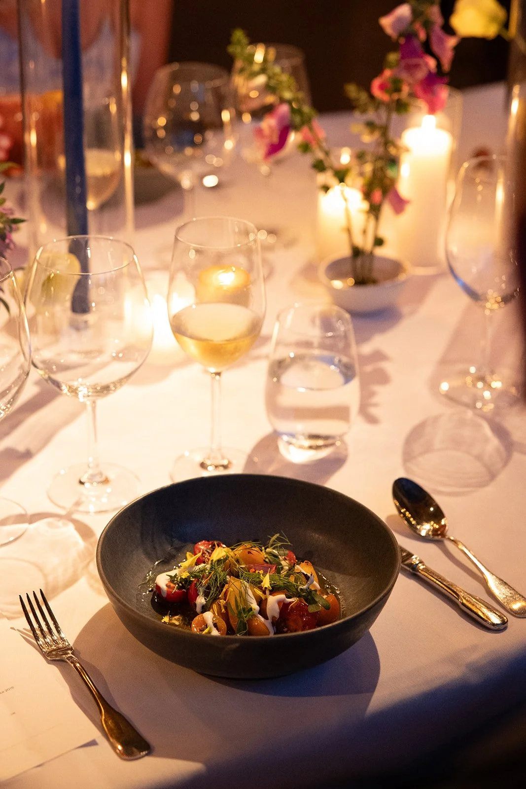 Gourmet wedding meal at elegantly set table under ambient lighting, reflecting Ashley Peraino's focus on creating memorable NYC wedding experiences.