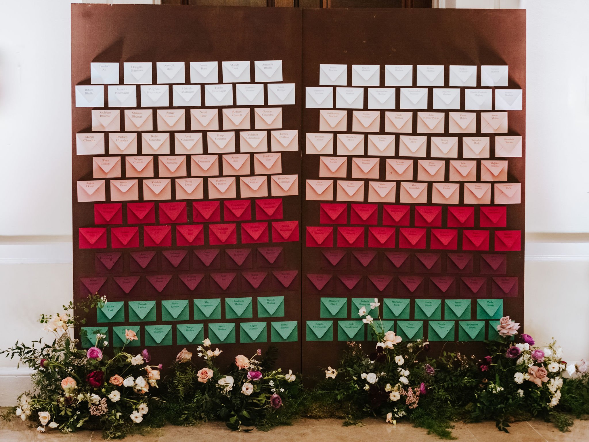 Red, burgundy and white escort card display, of single envelopes with the guests names inside