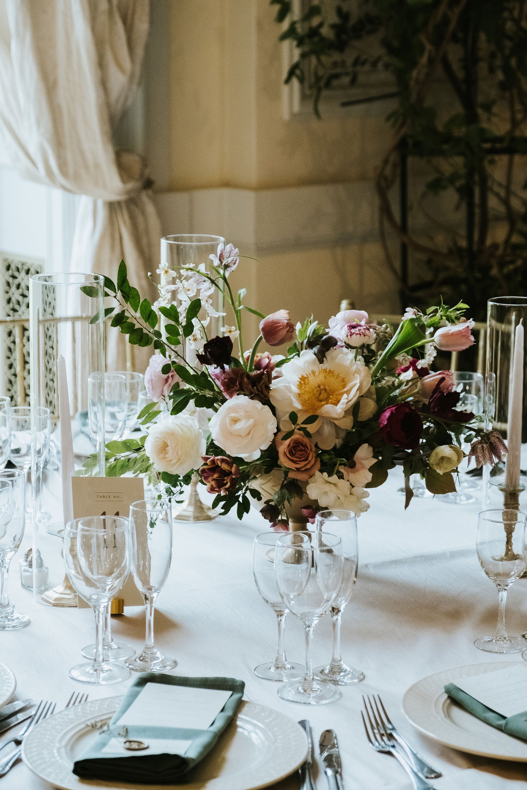 A formal wedding reception with burgundy and cream flower centerpieces