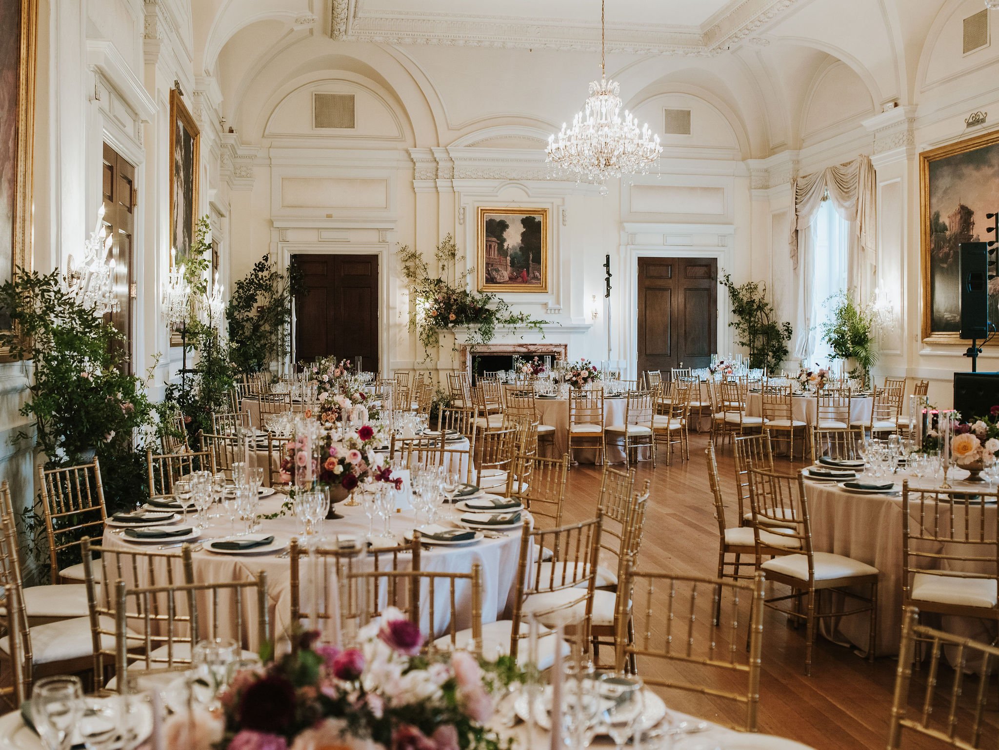 A formal wedding reception with burgundy and cream flower centerpieces inside the ballroom at Oheka Castle