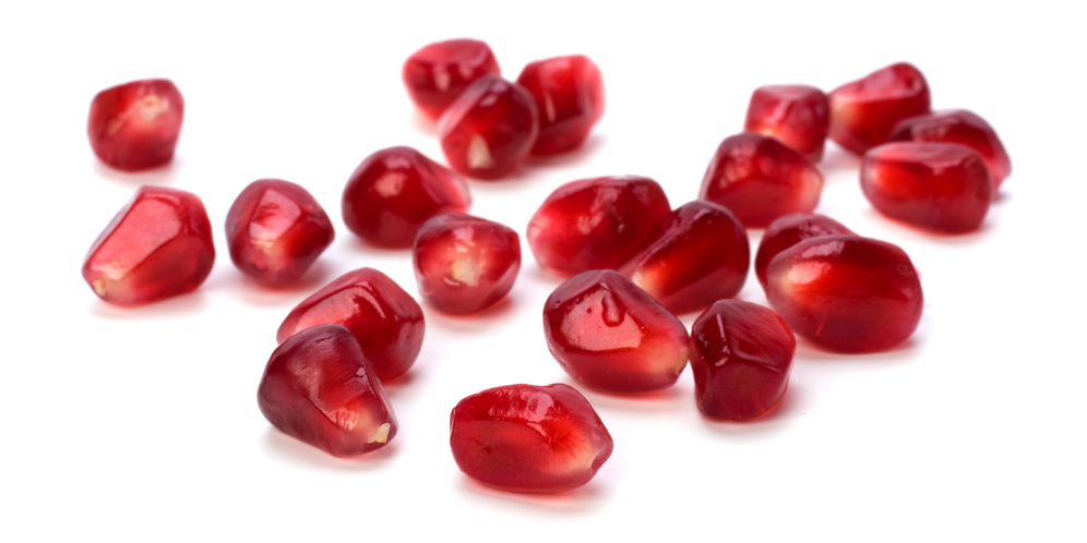 A small handful of vibrant pomegranate seeds with shadows