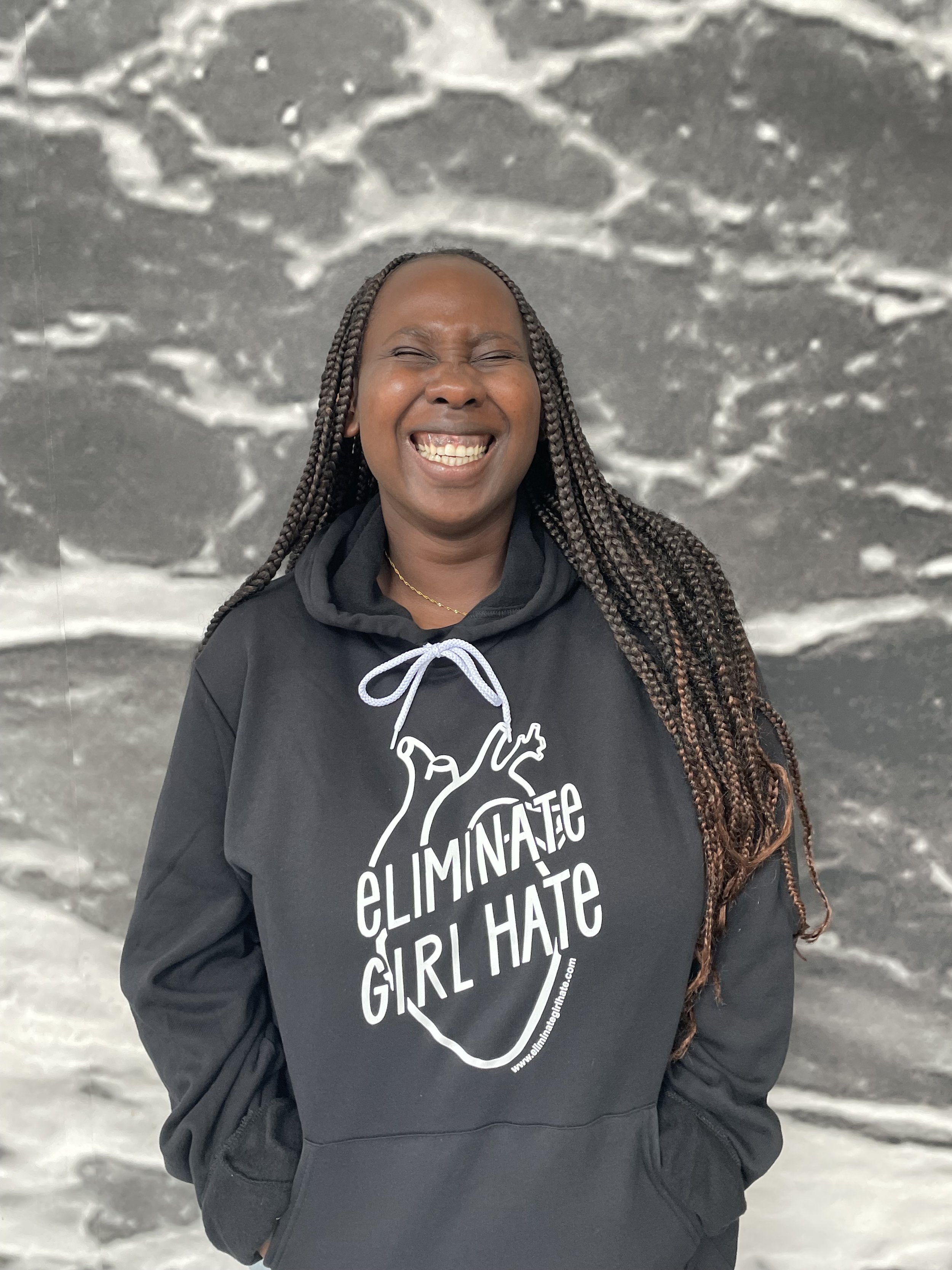 Young African American woman smiling and wearing the Eliminate Girl Hate unisex hoodie