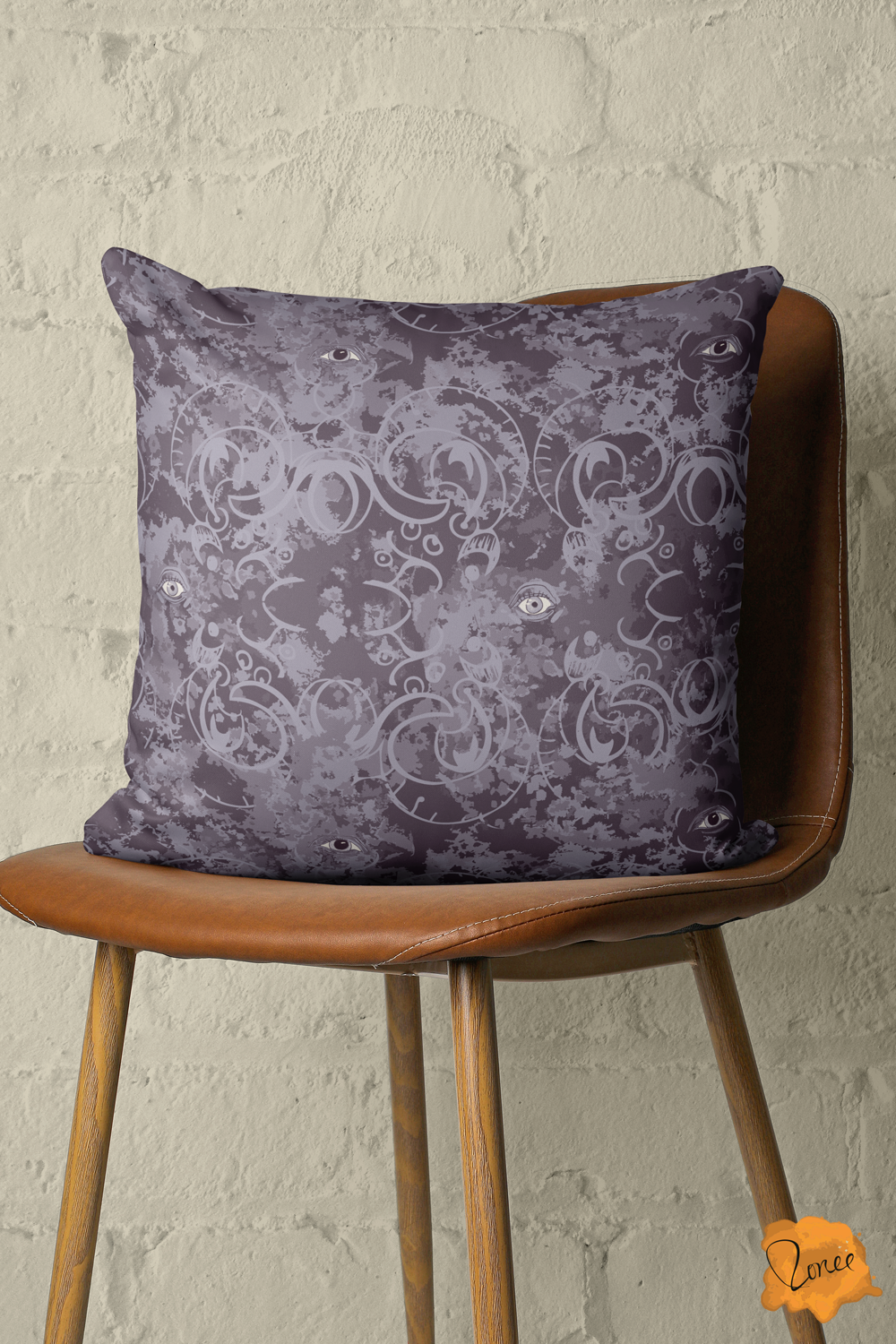 Deep muted purple throw pillow with mystical eyes on an ornate gothic fillagree pattern sits on a vintage and leather chair in front of a painted brick wall.