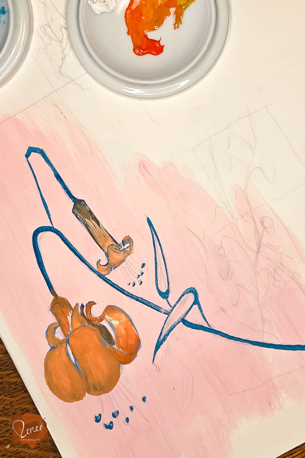 Close up flat lay image of a sketchbook with a gouache lily painting in progress and a ceramic palette dish with orange paint.