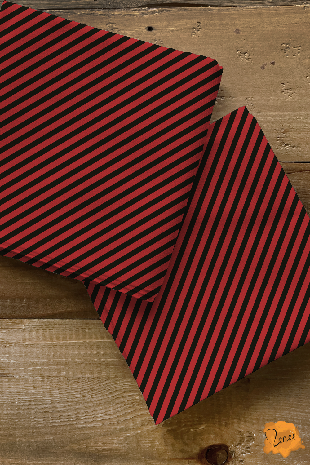 Two squares of folded quilting cotton with black and dark cherry red skinny diagonal stripes.