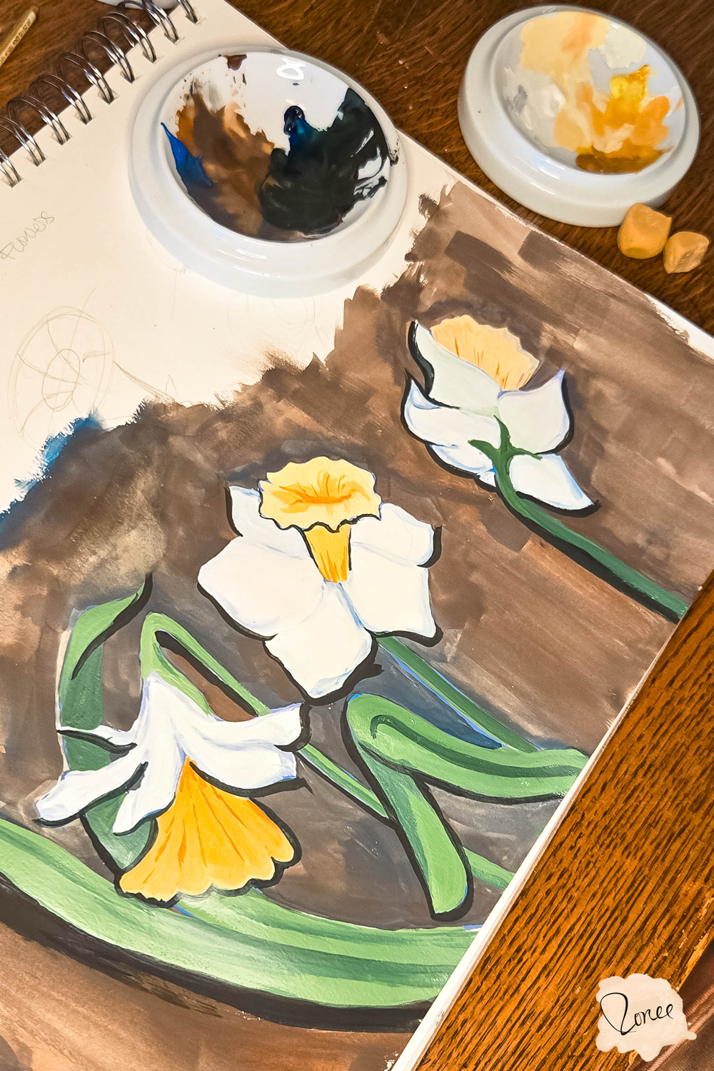 Close up flat lay image of a sketchbook with a gouache daffodils painting.
