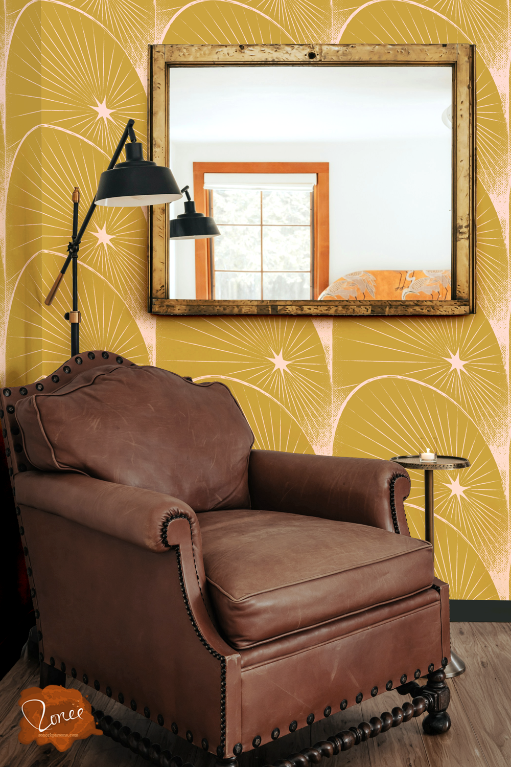 Old leather chair with a black floor lamp and vintage mirror in a room with mustard yellow wallpaper with an art deco pattern of starbursts in arches.