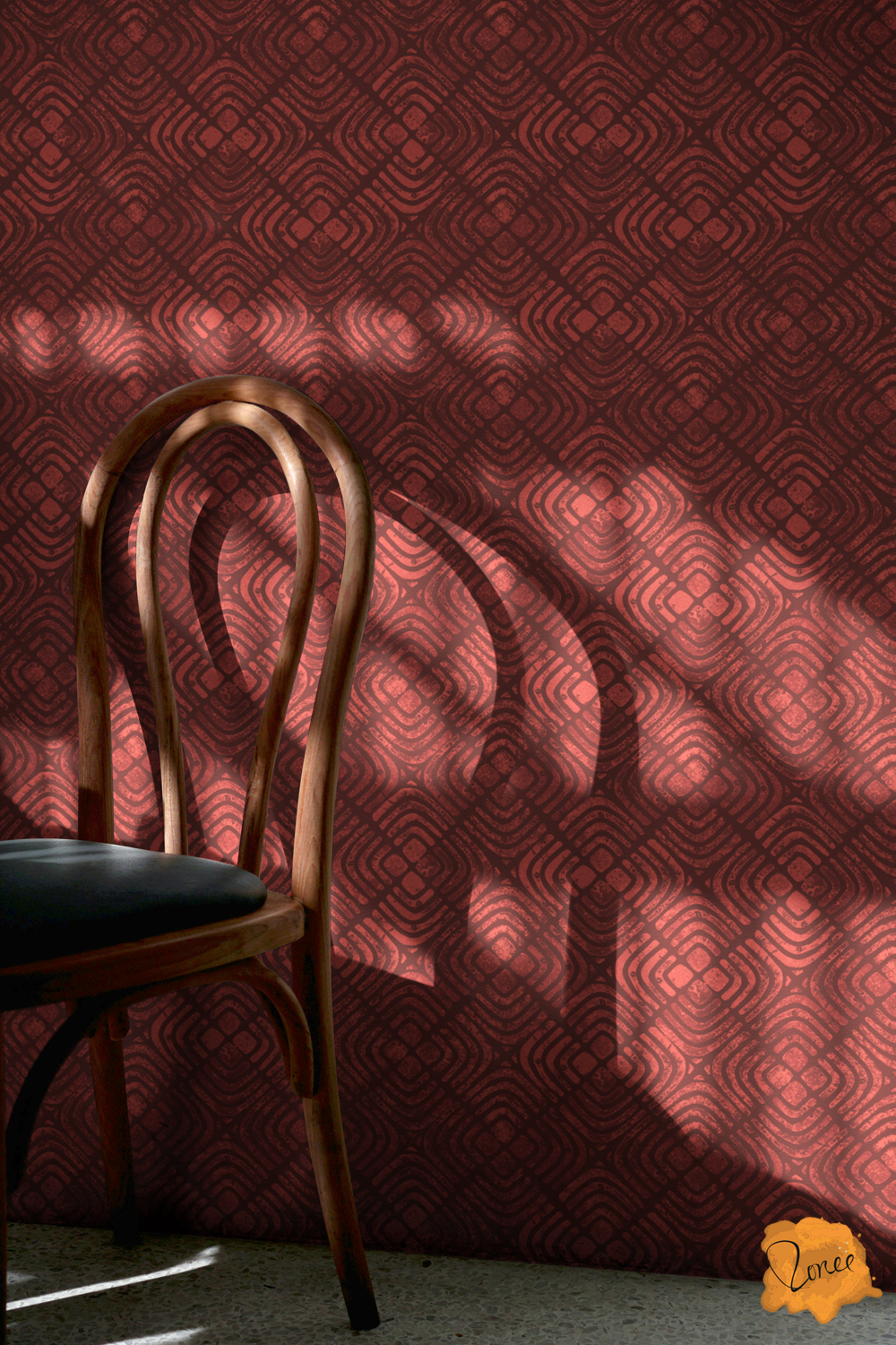 Muted cherry red boho block printed concentric squares wallpaper behind a cafe chair with sunlight coming in from the left.