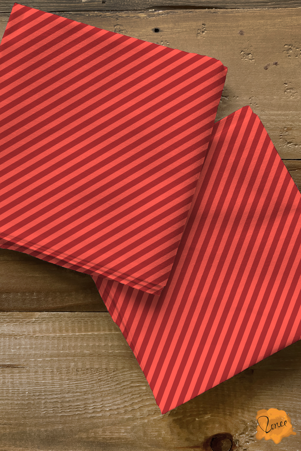 Two squares of folded quilting cotton with cherry red and pink skinny diagonal stripes.