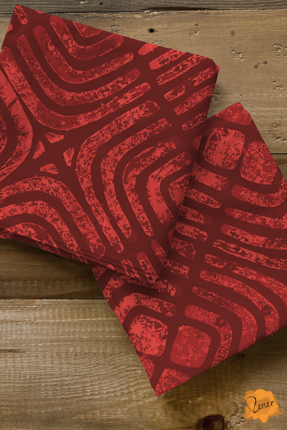 Two squares of folded quilting cotton with pattern of block printed concentric squares in deep muted cherry red..