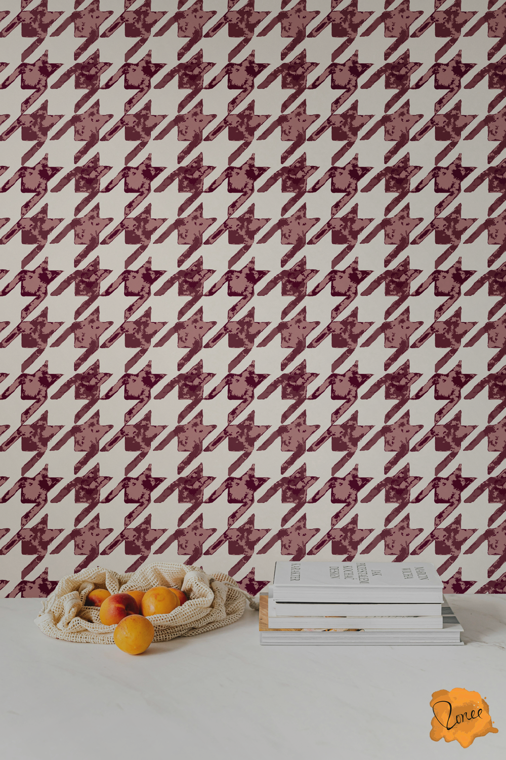 Rustic hand-painted houndstooth wallpaper in burgundy and mauve on off white behind a white kitchen counter with a stack of cookbooks and a mesh bag spilling peaches.