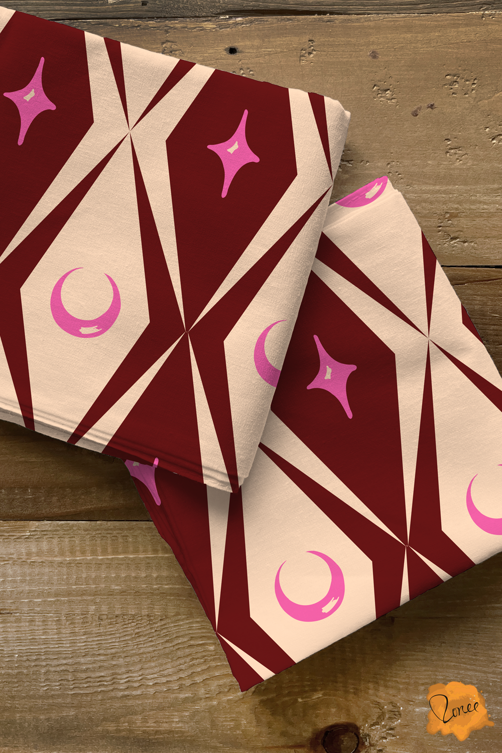 Two squares of folded quilting cotton with cream and burgundy diamonds with pink celestial moons and stars pattern..