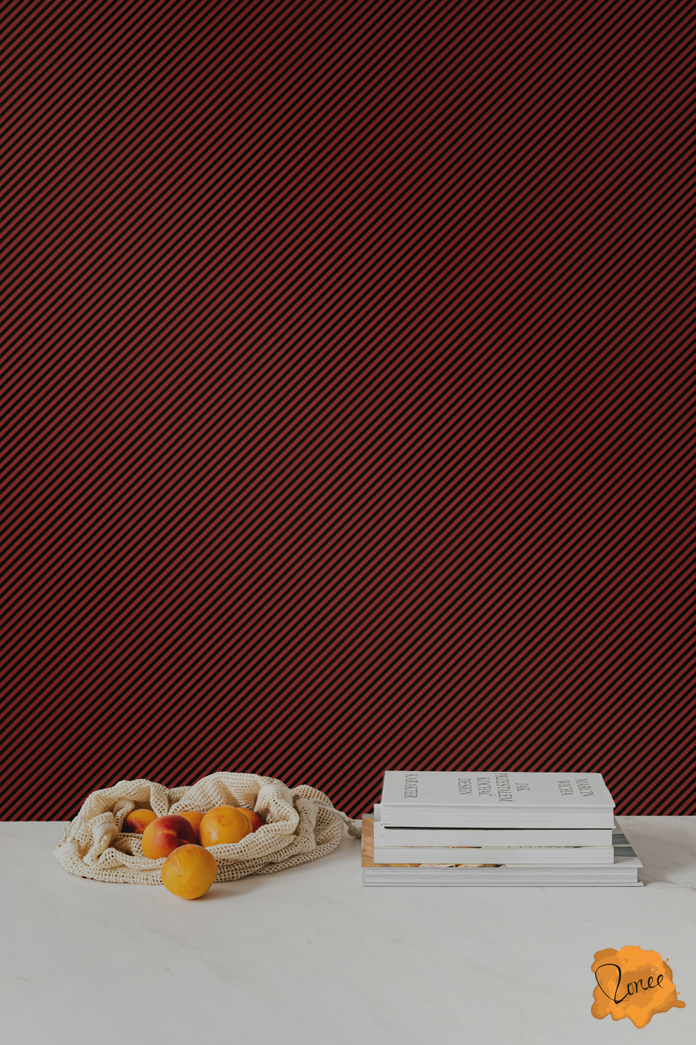 Skinny diagonal striped wallpaper in black and dark cherry red behind a white kitchen counter with a stack of cookbooks and a mesh bag spilling peaches.