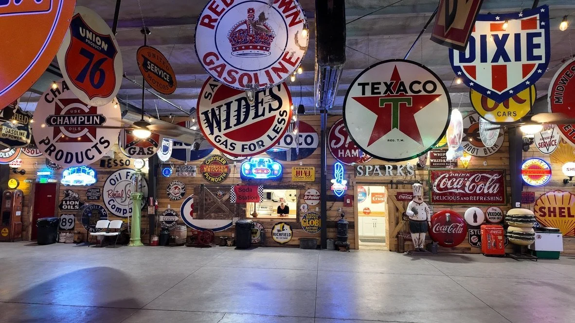 Open event floor ringed with neon and porcelain gas signs at Sparks Museum and Event Center in Provo